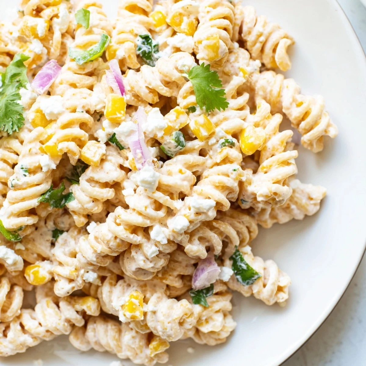 Creamy elote pasta salad loaded with charred corn, cotija cheese, and fresh cilantro in a rustic bowl