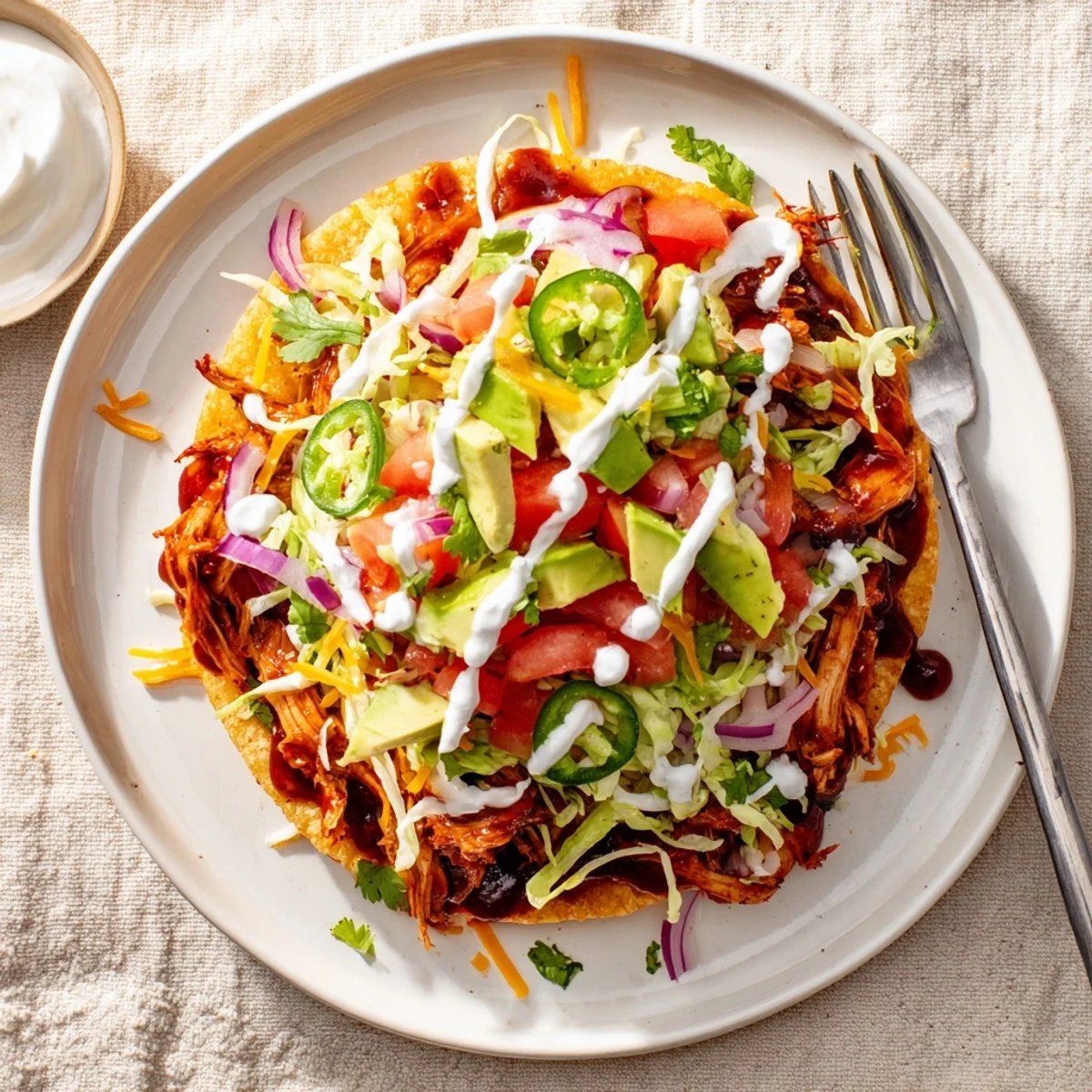 Crispy sweet smoky BBQ chicken tostadas loaded with fresh lettuce, tomatoes, and creamy avocado slices