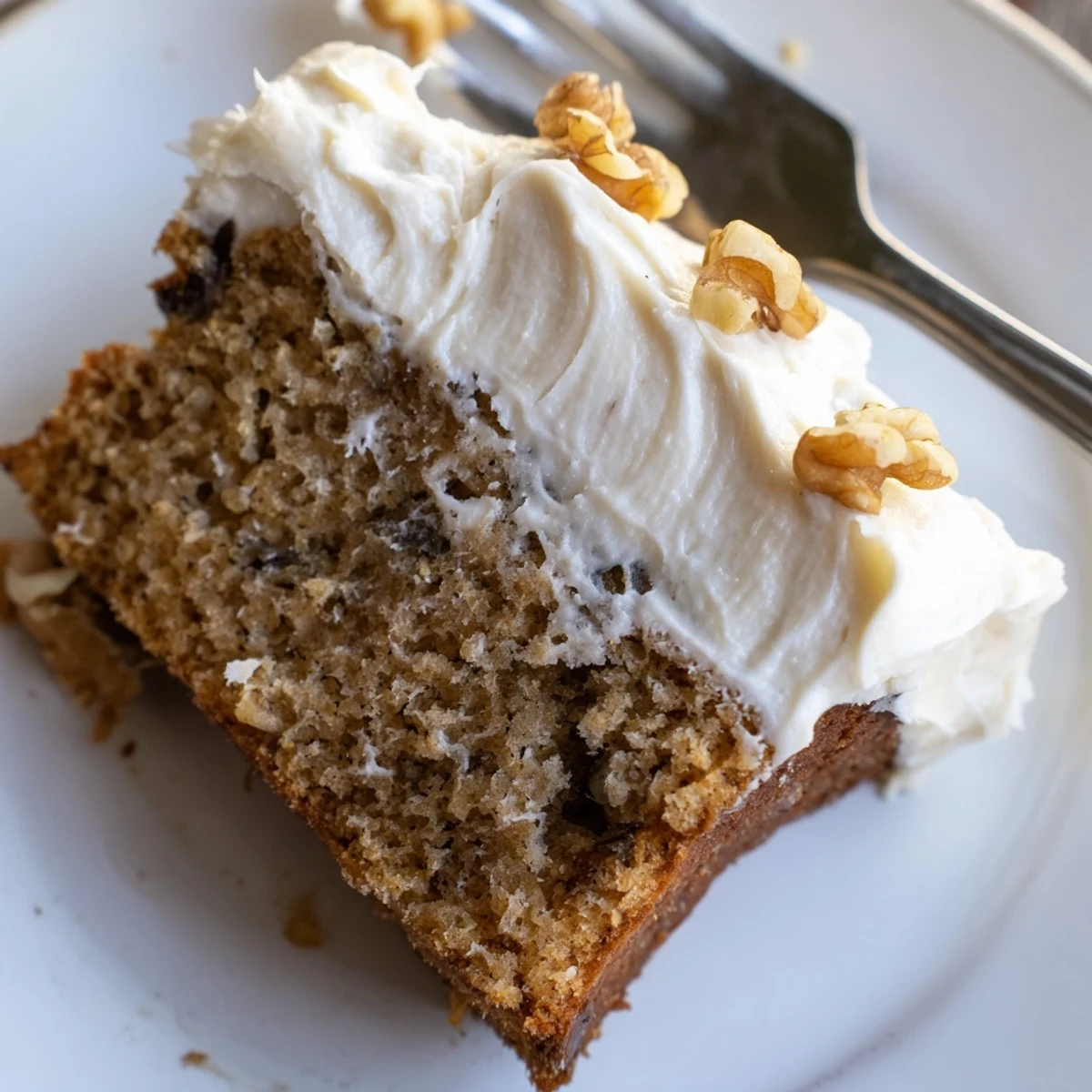 A generous slice of brown butter banana cake with thick cream cheese frosting on a rustic plate.