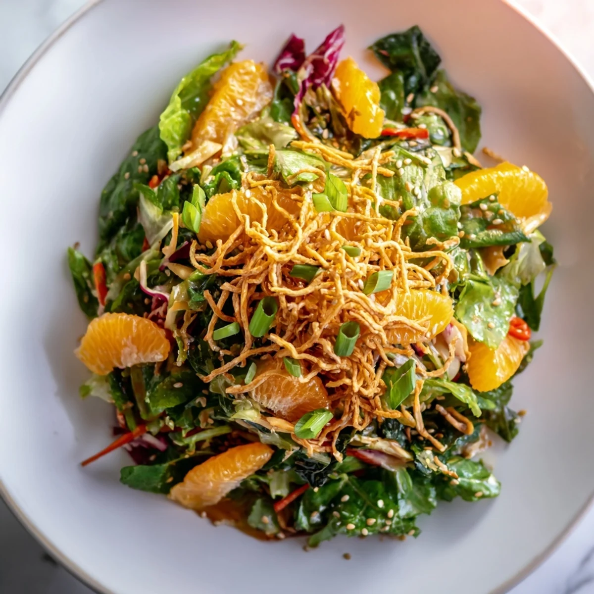 Crisp greens topped with mandarin oranges and crunchy sesame dressing in a wooden bowl