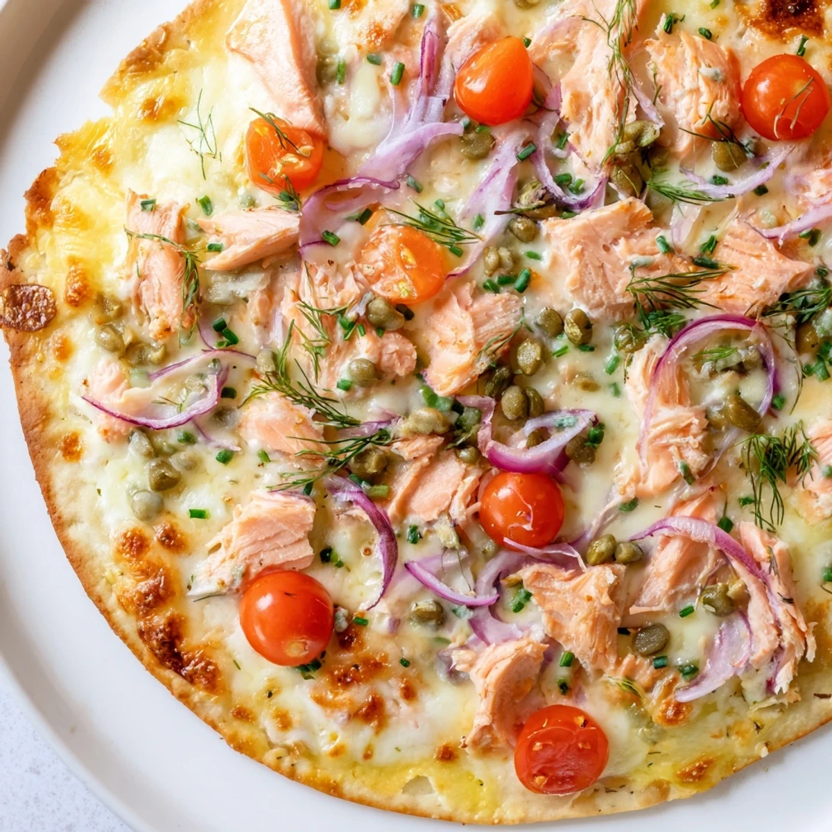 Crispy salmon tortilla pizza with melted mozzarella, cherry tomatoes, and fresh dill garnish