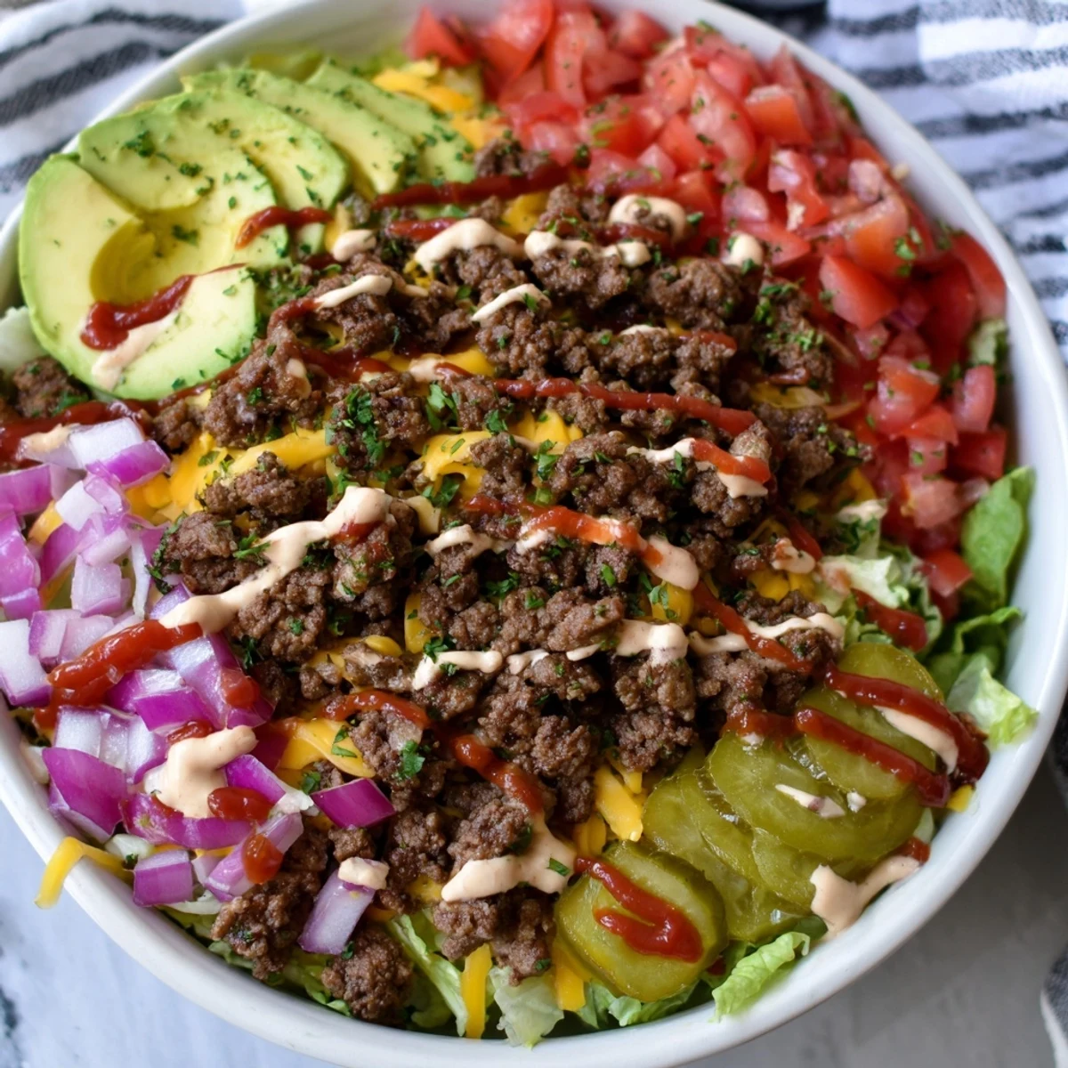 Deconstructed burger bowls drizzled with tangy sauce and sprinkled with sesame seeds