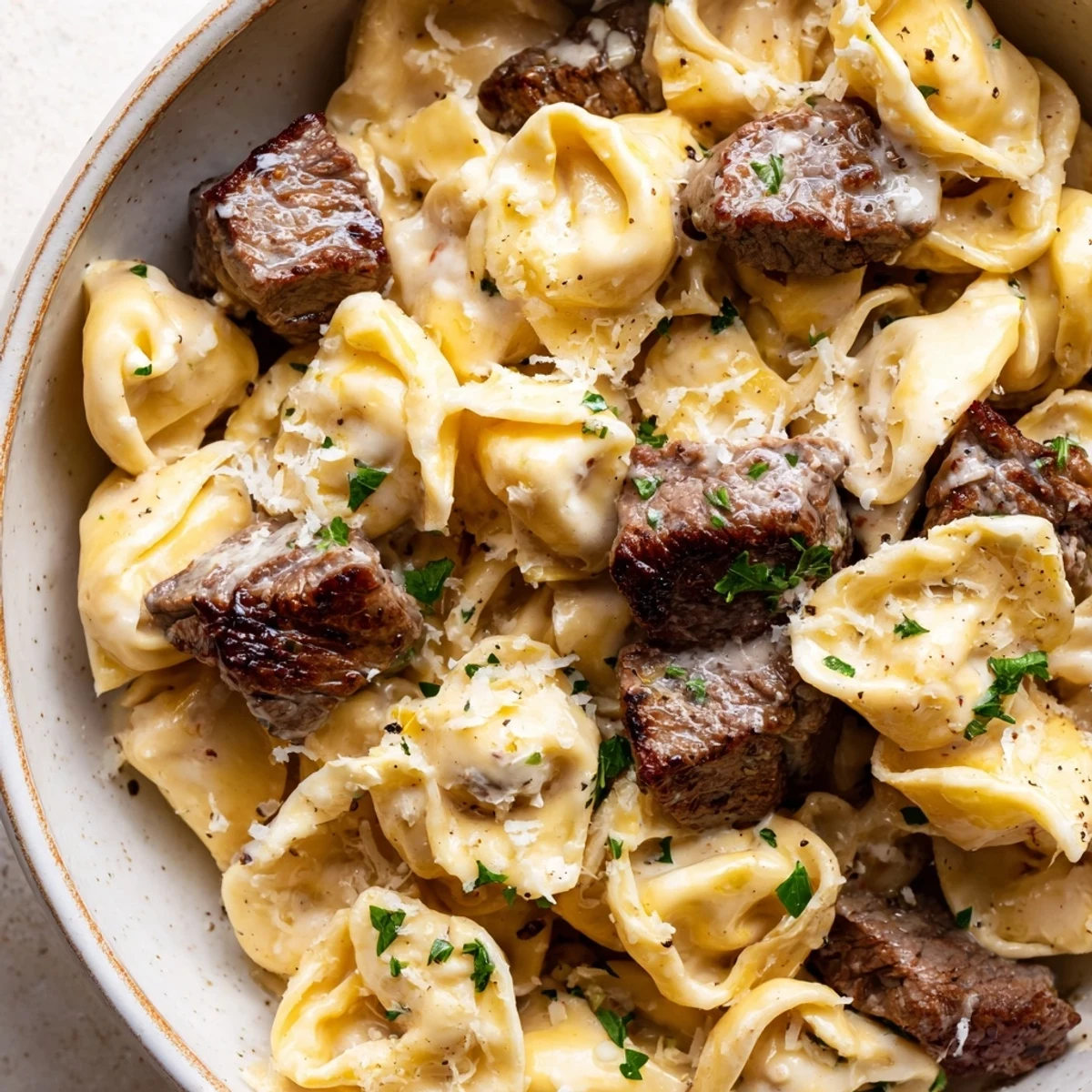 Creamy garlic steak tortellini in a golden parmesan sauce topped with fresh parsley