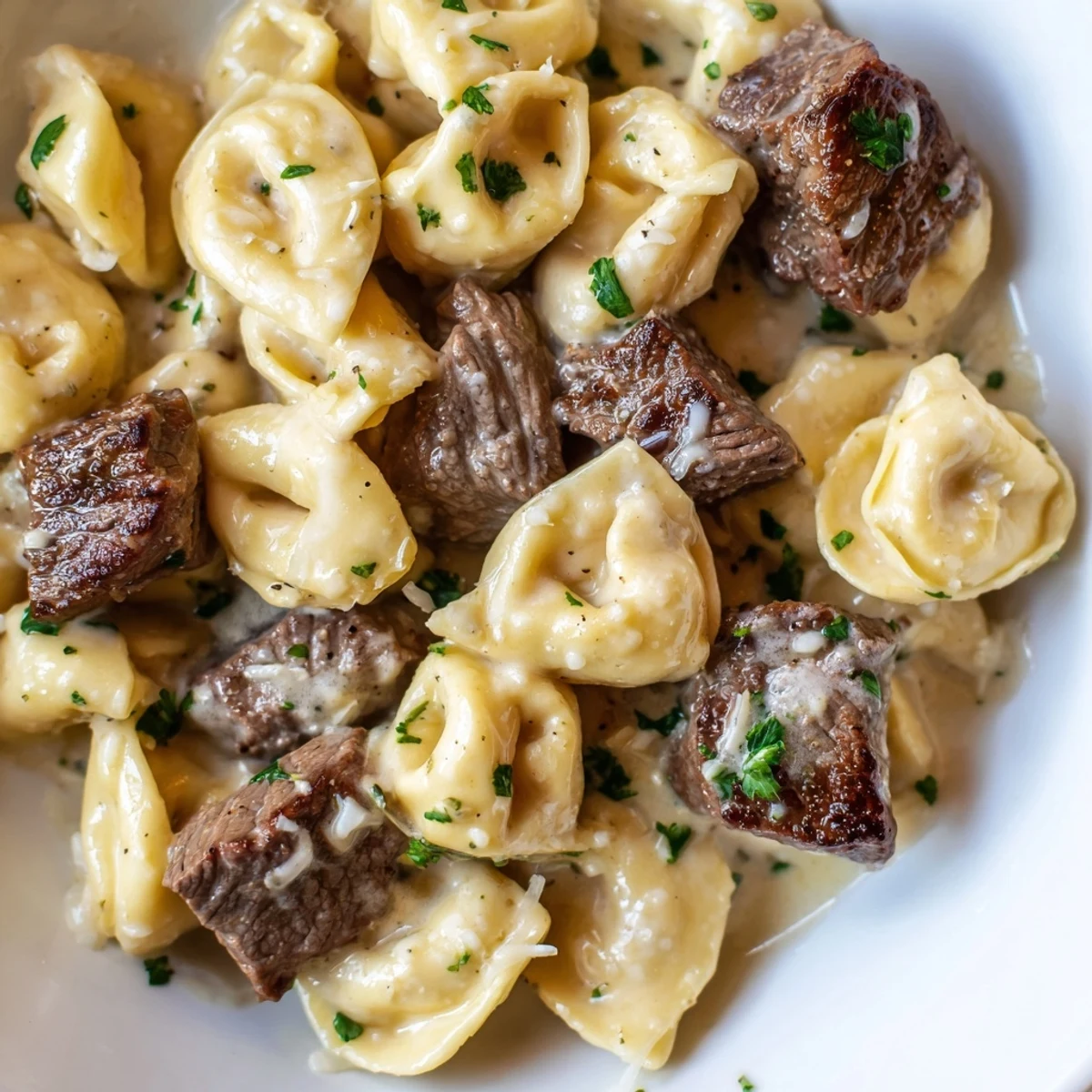 Steaming bowl of garlic steak tortellini with seared sirloin and a velvety cream sauce