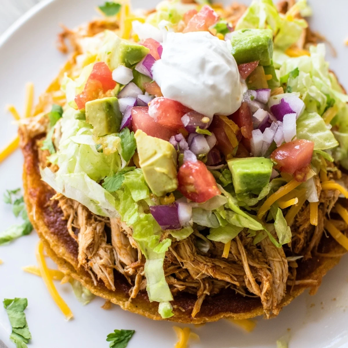 Golden Chicken Tostadas piled high with fresh lettuce, cheese, and creamy guacamole  