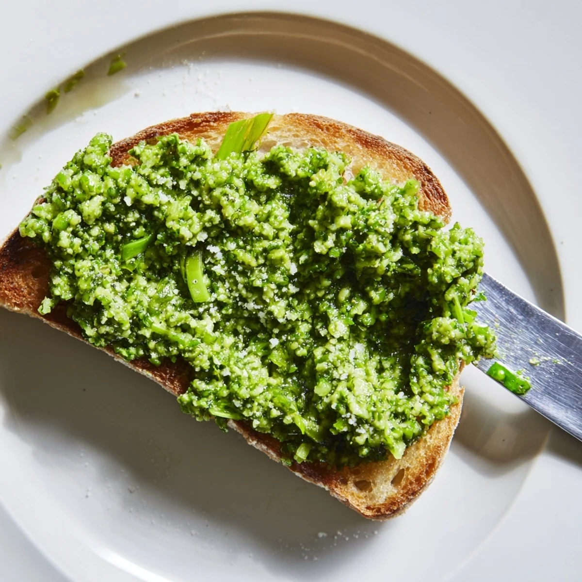 Vibrant garlic scape pesto drizzled over fresh pasta with basil garnish  