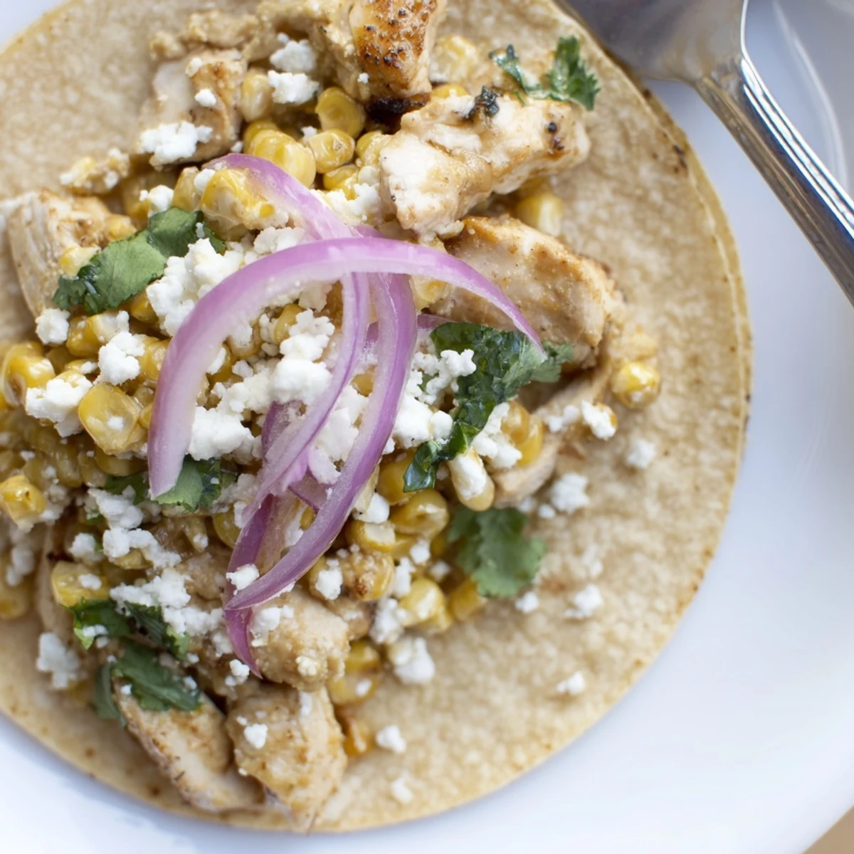 Golden street corn chicken tacos topped with creamy cotija and fresh cilantro.  