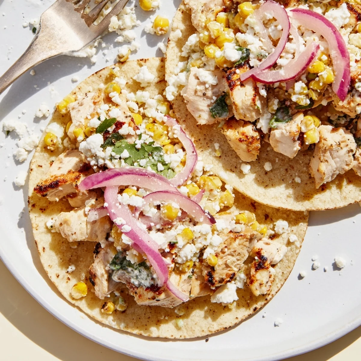 Juicy grilled chicken tacos with zesty street corn and crumbled cheese filling.  