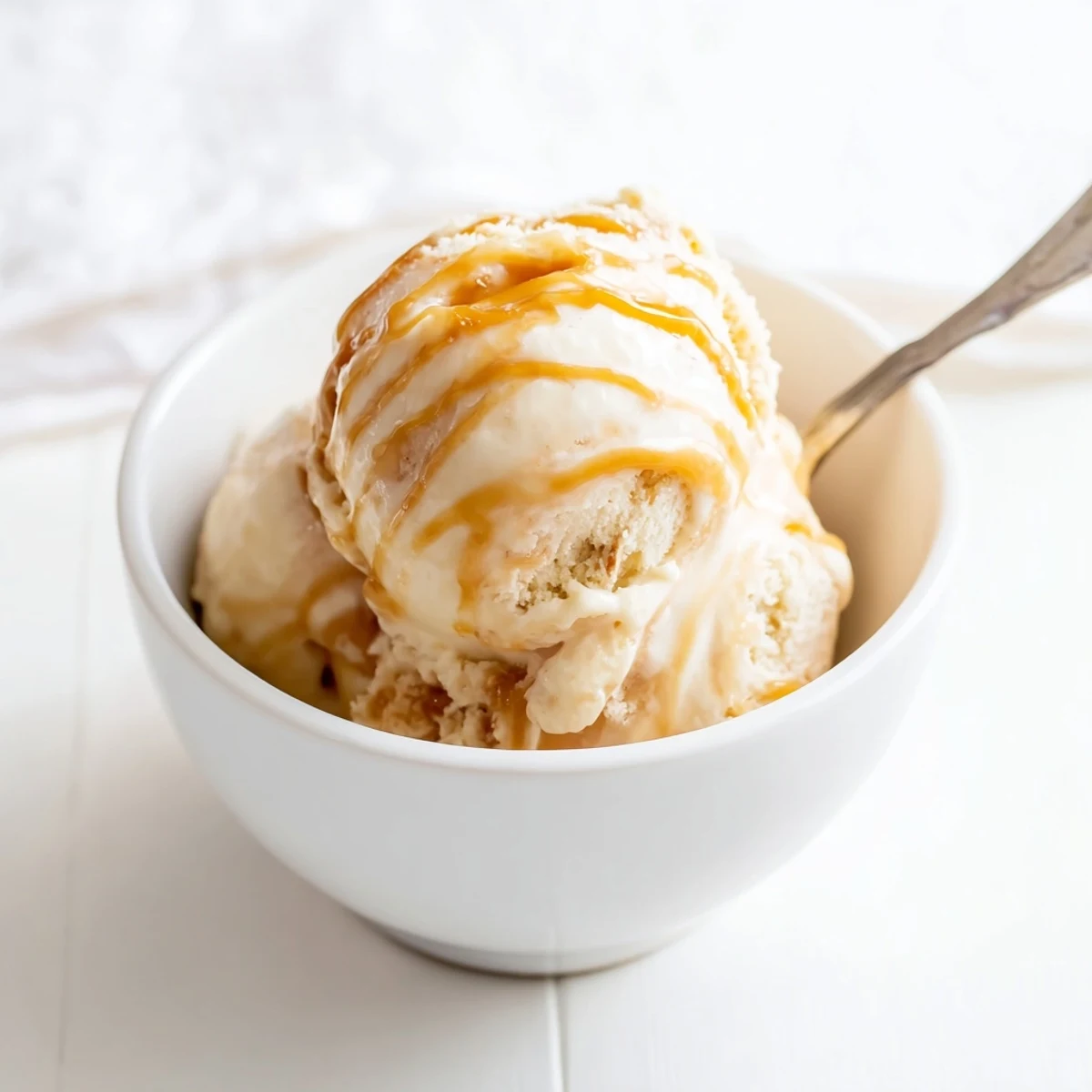 Smooth egg-free salted caramel ice cream showing swirled layers in a chilled glass dish.