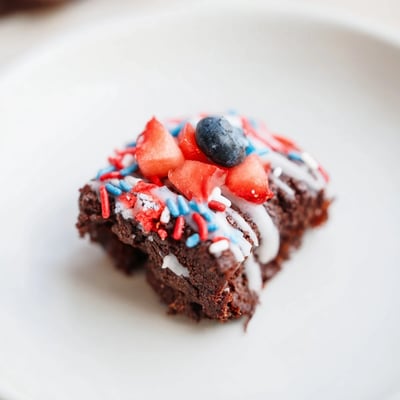 Glazed Fourth of July brownie bites decorated with fresh fruit for patriotic parties.